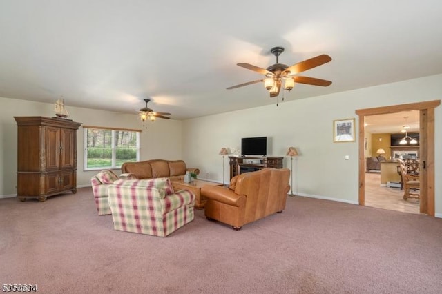 living room featuring baseboards, light carpet, and a ceiling fan