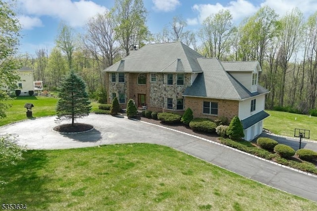 view of front of house with curved driveway, brick siding, and a front yard