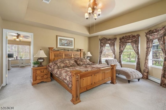bedroom with a tray ceiling, baseboard heating, and light carpet