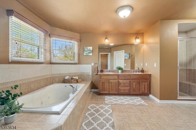 full bathroom featuring double vanity, a shower stall, a sink, baseboards, and a whirlpool tub