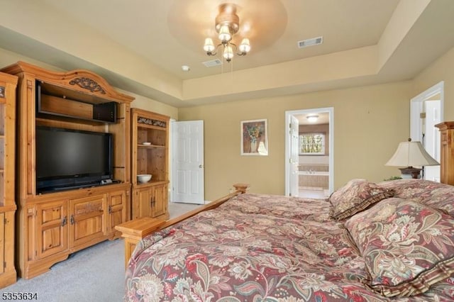 bedroom featuring a raised ceiling, ensuite bathroom, light carpet, and visible vents