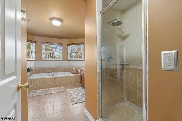 bathroom featuring tile patterned flooring, a bath, and a shower stall