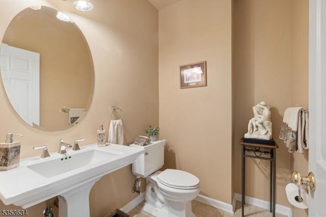 half bath with baseboards, tile patterned floors, and toilet