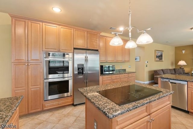 kitchen featuring light brown cabinets, open floor plan, a center island, dark stone countertops, and appliances with stainless steel finishes