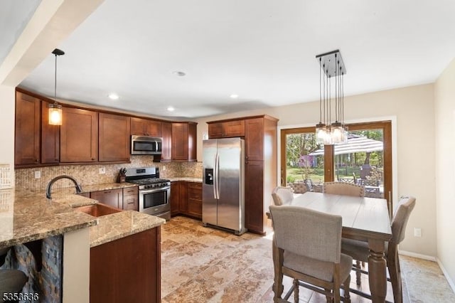 kitchen with decorative backsplash, decorative light fixtures, light stone countertops, a sink, and stainless steel appliances