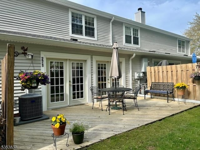 rear view of house featuring cooling unit, a deck, a chimney, outdoor dining space, and french doors