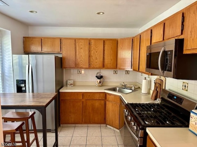 kitchen with appliances with stainless steel finishes, tasteful backsplash, light countertops, and a sink