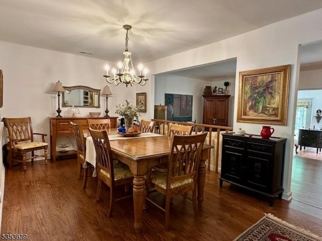 dining room with dark wood-type flooring and a chandelier