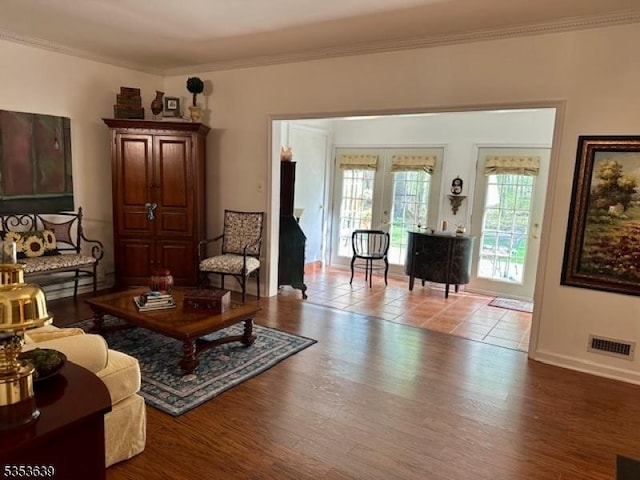 living area with crown molding, visible vents, baseboards, french doors, and wood finished floors