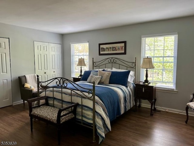 bedroom featuring dark wood-style flooring, multiple closets, and baseboards