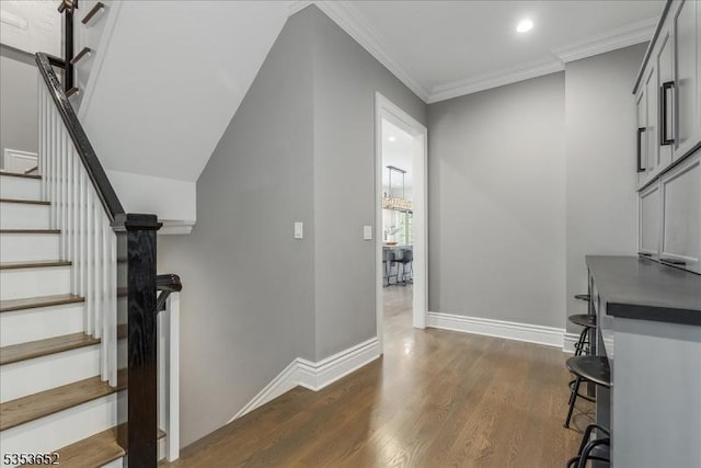 staircase with baseboards, ornamental molding, recessed lighting, and wood finished floors