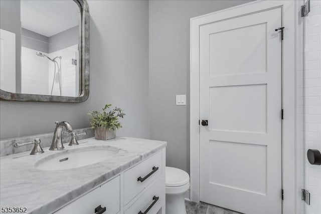 full bathroom featuring toilet, tiled shower, and vanity