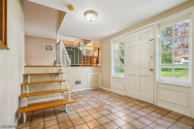 foyer with visible vents, stairs, light tile patterned floors, and a healthy amount of sunlight