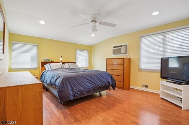 bedroom featuring baseboards, a wall mounted AC, wood finished floors, and visible vents