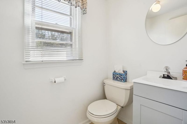 bathroom featuring toilet, baseboards, and vanity