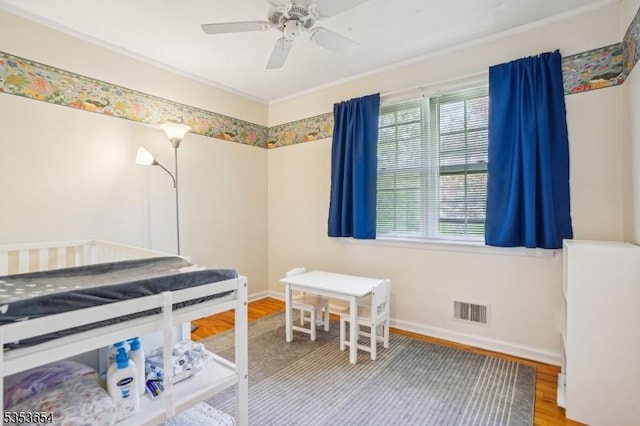 bedroom featuring baseboards, visible vents, ornamental molding, and wood finished floors