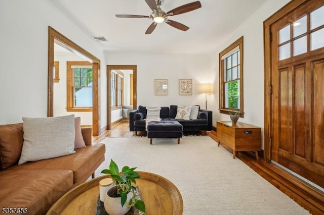 living area with plenty of natural light, wood finished floors, and ceiling fan