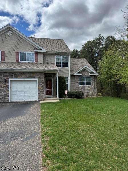 traditional-style house with an attached garage, a front lawn, aphalt driveway, and stone siding