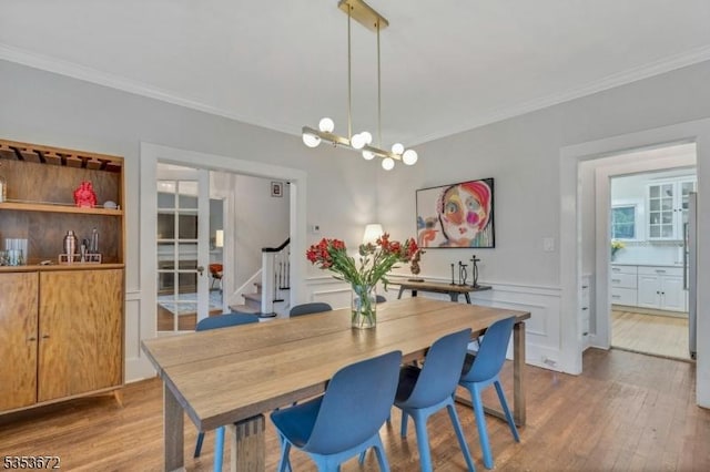 dining area with ornamental molding, stairs, wood finished floors, and a chandelier