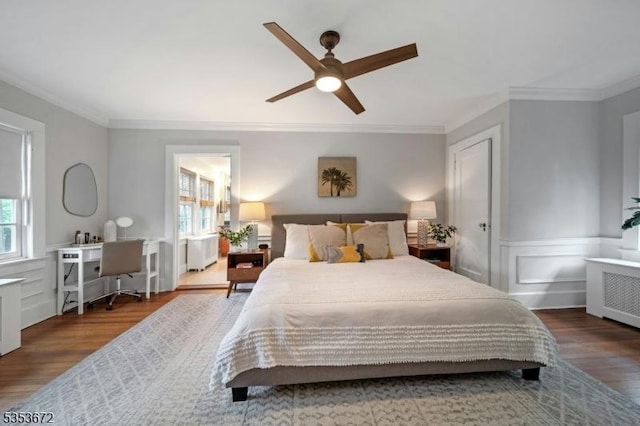 bedroom with radiator heating unit, wood finished floors, ornamental molding, a wainscoted wall, and ceiling fan