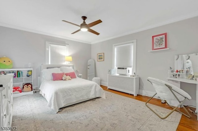 bedroom featuring ornamental molding, radiator, wood finished floors, ceiling fan, and cooling unit
