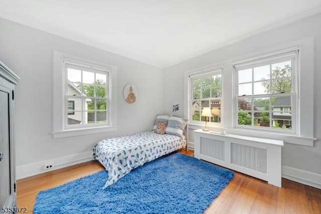 bedroom featuring radiator, wood finished floors, and baseboards