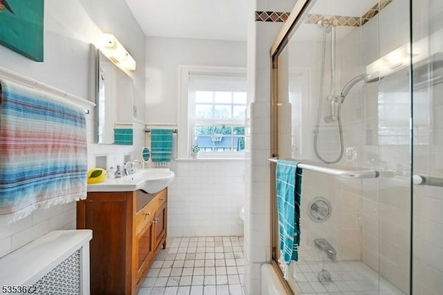 bathroom with tile walls, vanity, tile patterned floors, a wainscoted wall, and toilet