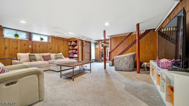 living room featuring wooden walls, stairway, and carpet flooring
