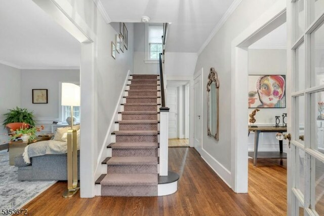 stairway featuring wood finished floors and crown molding