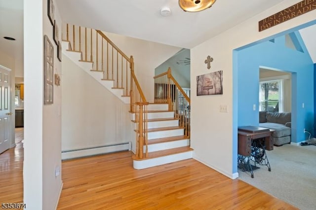 stairs with baseboards, a baseboard radiator, and wood finished floors