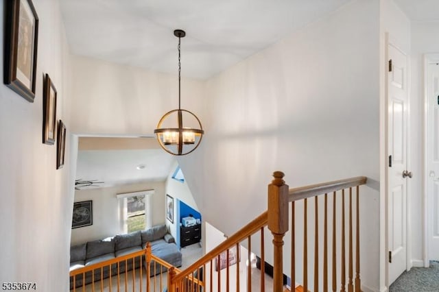 hallway featuring baseboards, carpet flooring, a chandelier, and an upstairs landing