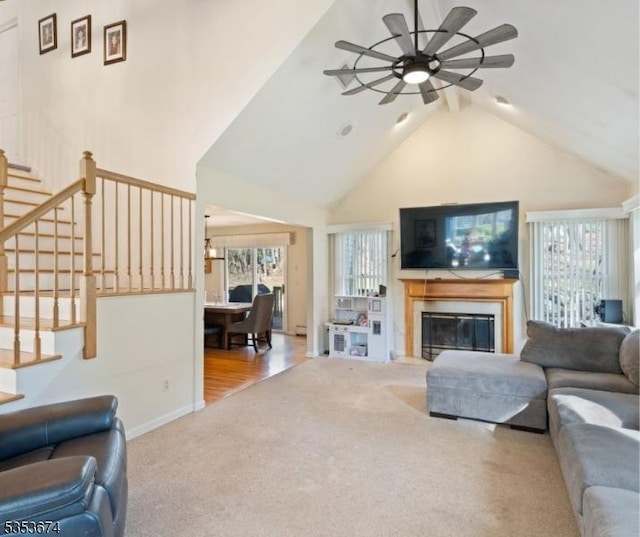 living room with carpet flooring, ceiling fan, a glass covered fireplace, and a wealth of natural light