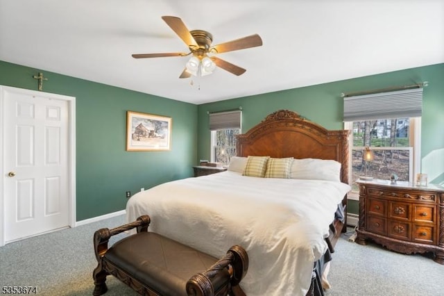 carpeted bedroom featuring baseboards, ceiling fan, a baseboard heating unit, and multiple windows
