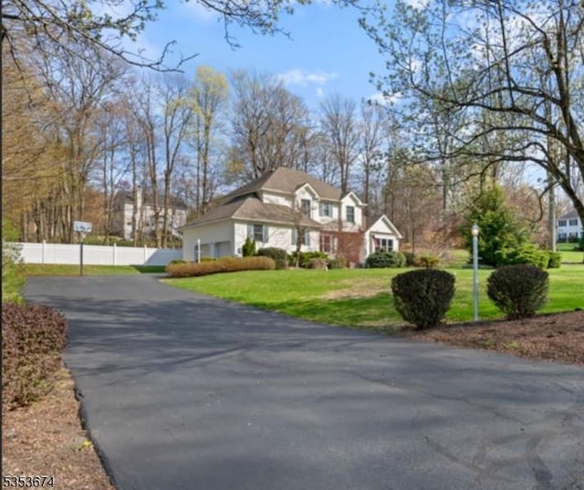cape cod home featuring aphalt driveway, fence, and a front yard