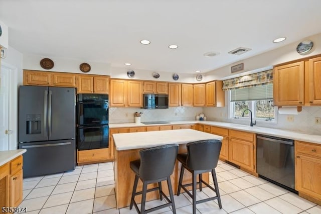 kitchen with a sink, a kitchen island, black appliances, and light countertops