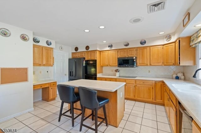 kitchen featuring visible vents, light tile patterned flooring, light countertops, a sink, and black appliances