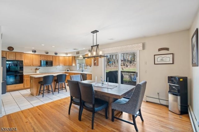 dining room with recessed lighting, a baseboard heating unit, and light wood finished floors