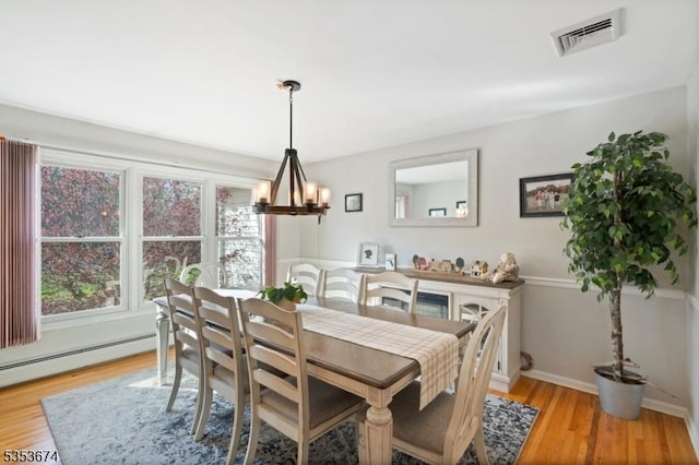 dining space with visible vents, baseboards, light wood-type flooring, a baseboard radiator, and a notable chandelier