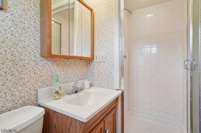full bathroom featuring vanity, wallpapered walls, a stall shower, and toilet