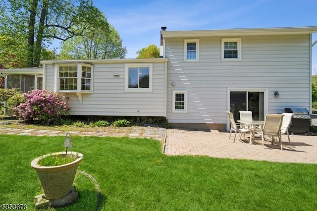 rear view of property with a lawn, a sunroom, and a patio area