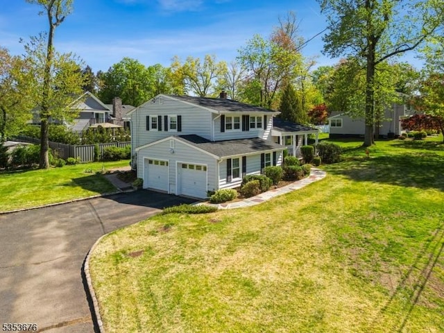 traditional home with a chimney, a garage, fence, aphalt driveway, and a front lawn