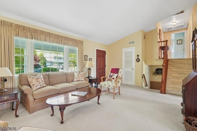 carpeted living area with vaulted ceiling, stairs, and visible vents