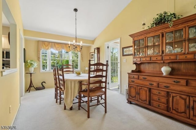 dining space with an inviting chandelier, light carpet, and vaulted ceiling