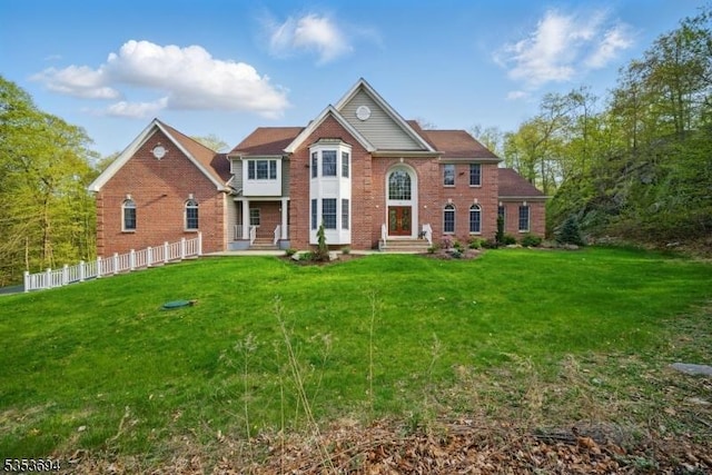 back of house with fence, a yard, and brick siding