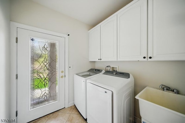 washroom featuring a sink, light tile patterned floors, cabinet space, and washing machine and clothes dryer