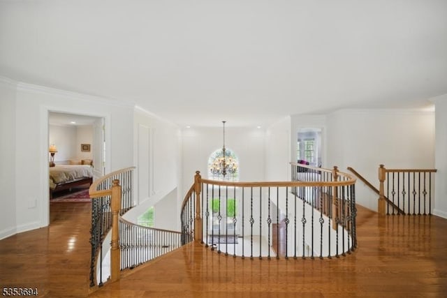 corridor with crown molding, baseboards, wood finished floors, and an upstairs landing