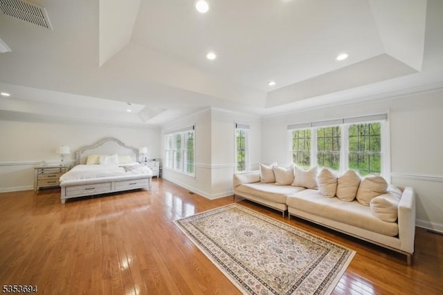 bedroom featuring wood-type flooring, baseboards, visible vents, and a raised ceiling