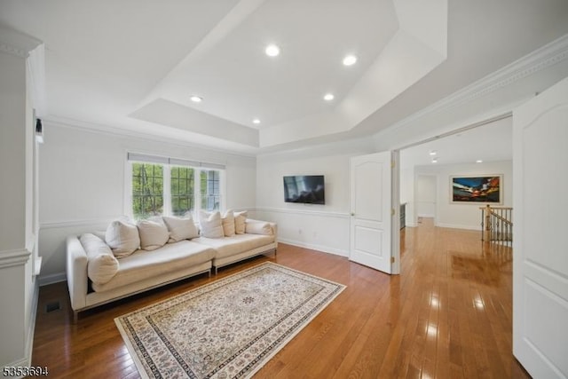 living room with visible vents, ornamental molding, hardwood / wood-style floors, recessed lighting, and a tray ceiling