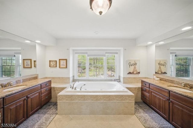 bathroom featuring a garden tub, a sink, and a wealth of natural light