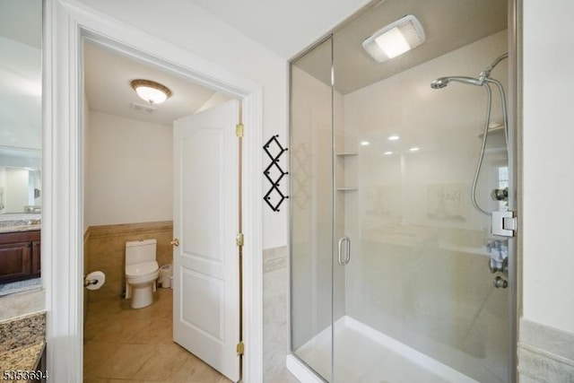 full bathroom with vanity, tile patterned flooring, toilet, a wainscoted wall, and a shower stall